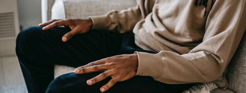 A man sitting on a couch with his hands resting on his lap.