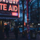 A street at night with a lit up Rite Aid Pharmacy Sign.
