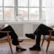 Two people sitting across from each other in chairs. One person is talking, and the other is listening and writing down notes.
