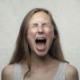 A close up of a woman closing her eyes screaming.