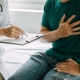 Man grasping his heart while doctor writes down on clipboard